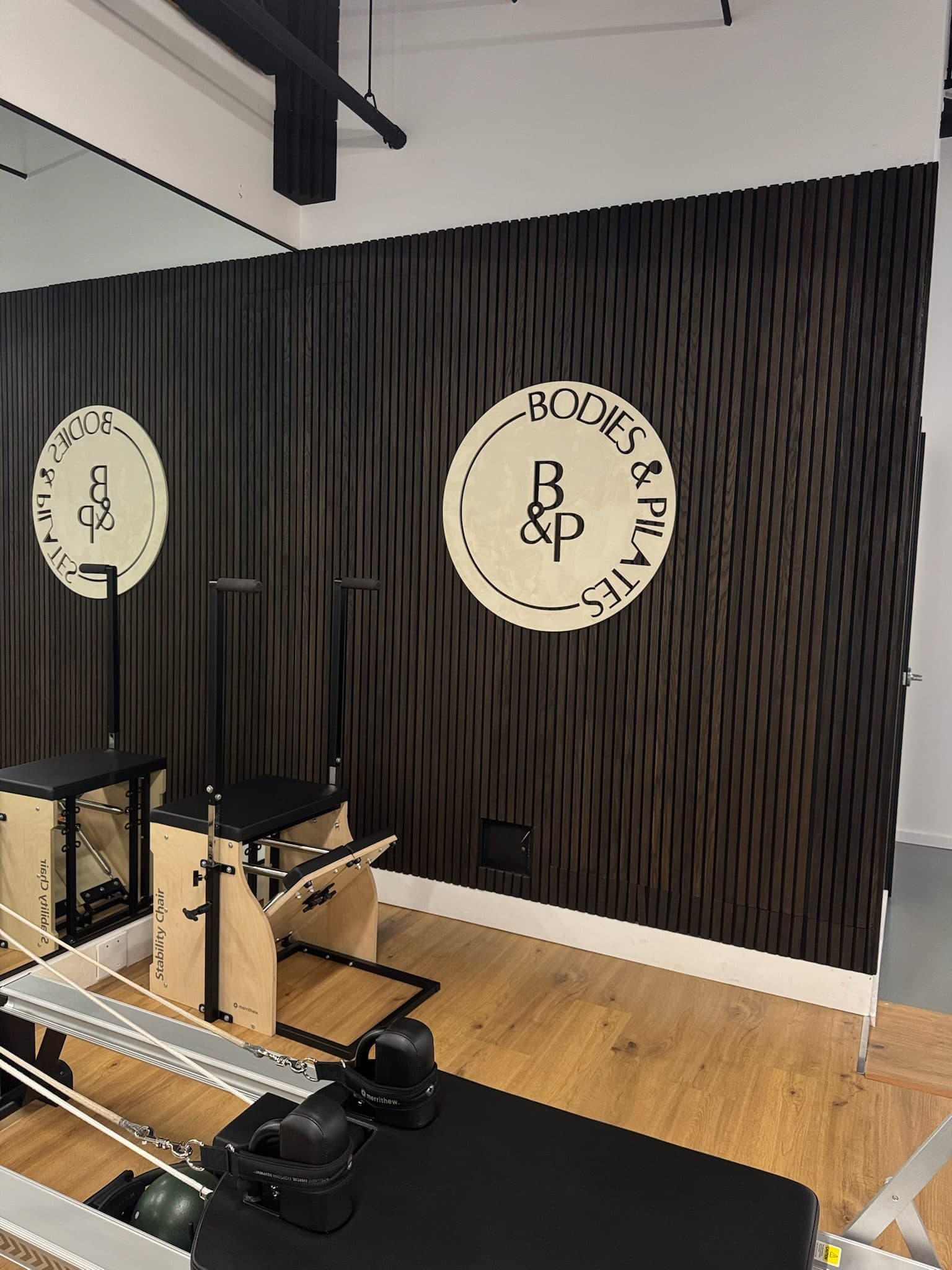 Pilates chair in front of the logo wall at Bodies and Pilates in North Hollywood